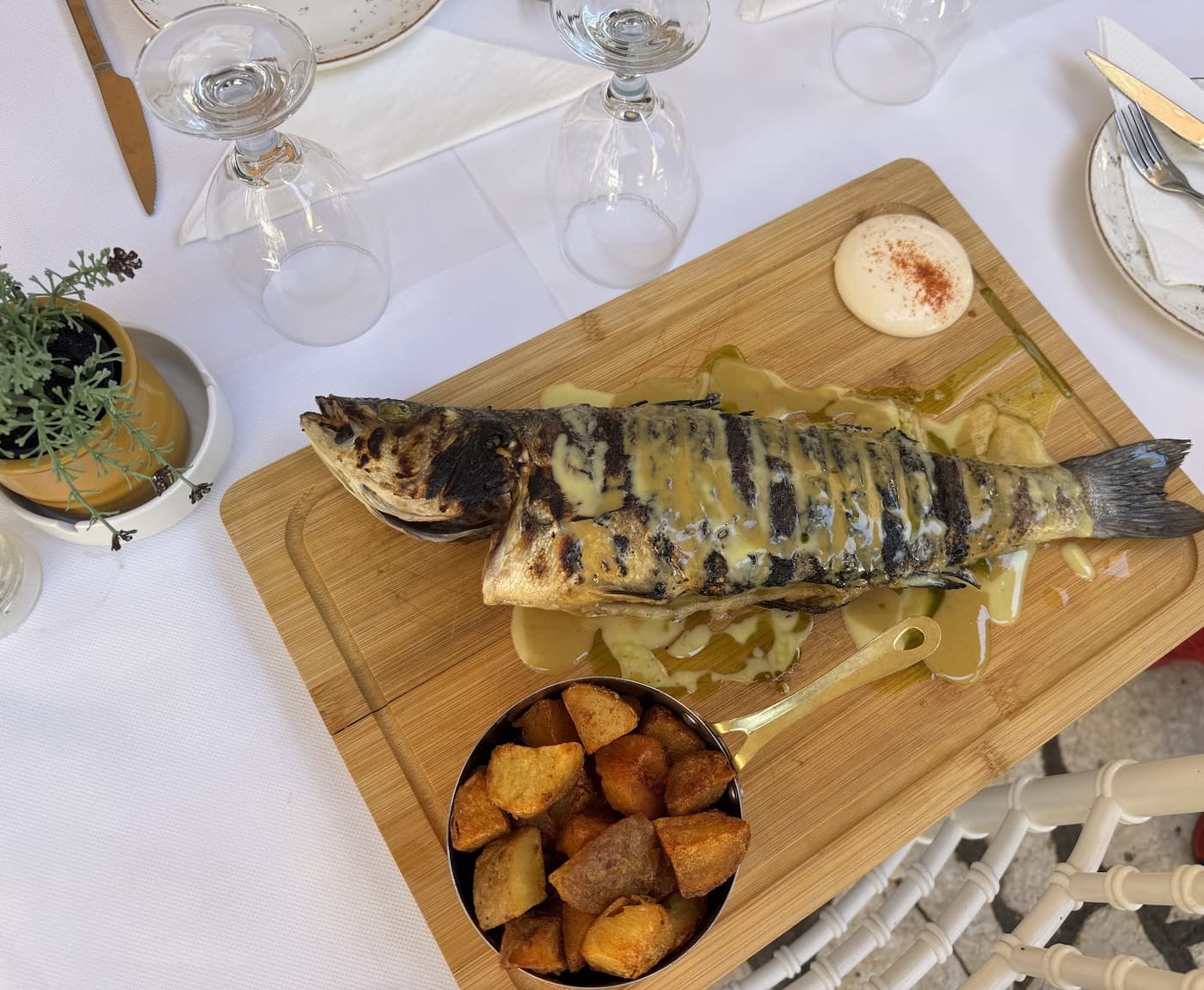 Whole grilled fish on a wooden board with roasted potatoes